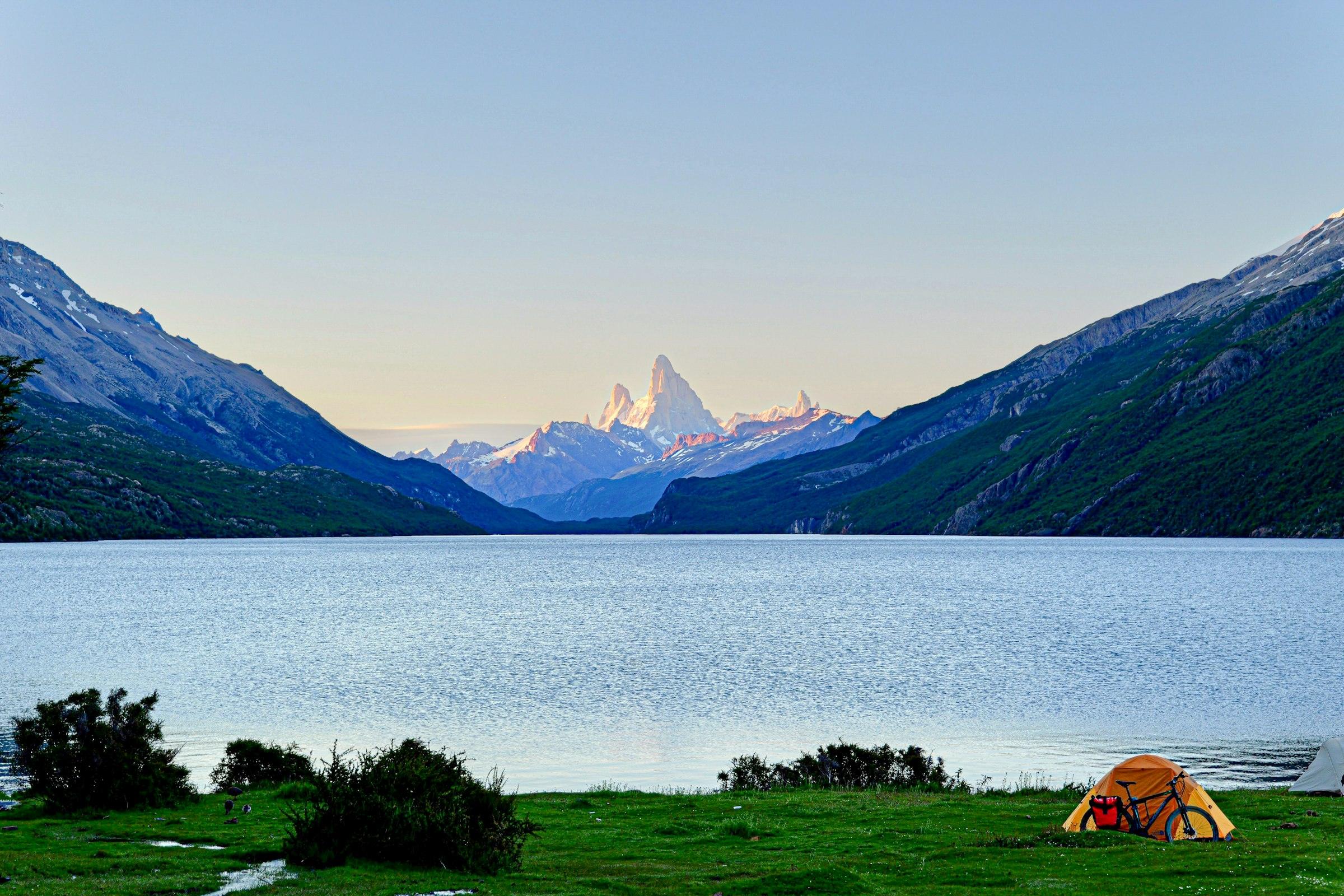 Lago patagónico con el cerro Fitz Roy de fondo y una carpa en la orilla